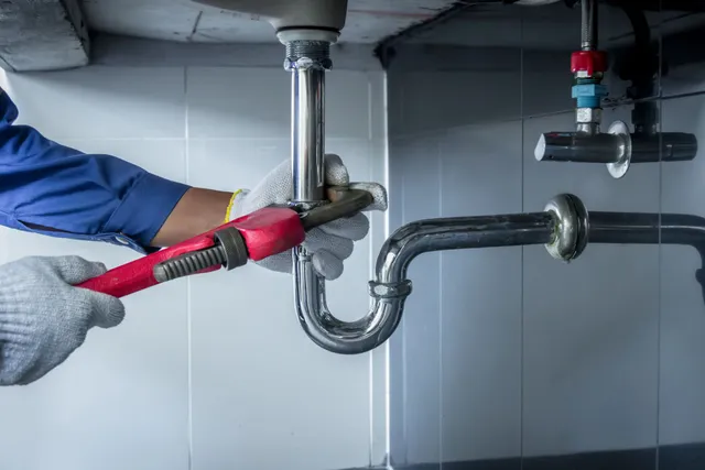 Professional plumber repairing pipes under a sink